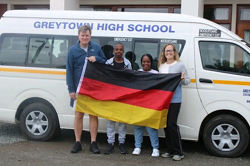 Unsere Gäste aus Südafrika noch in Greytown mit deutscher Flagge vor einem Schulbus